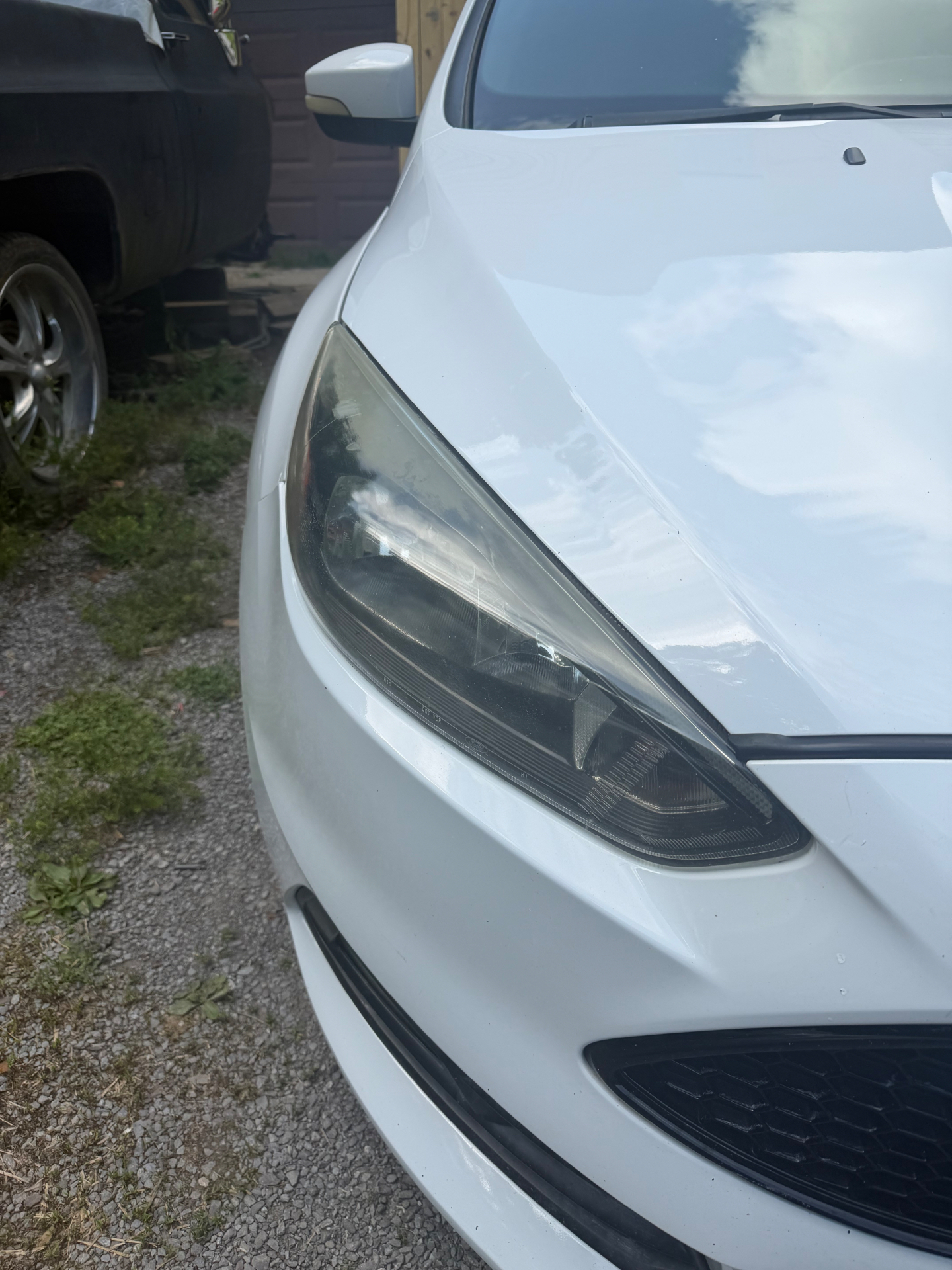 Cloudy headlight before restoration on a white hatchback.